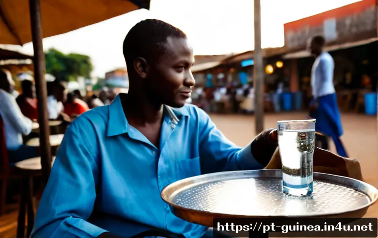 기니에서 가장 많이 소비되는 음료 - Photorealistic outdoor café scene in Conakry, Guinea, featuring a clear glass of fresh water beside ...
